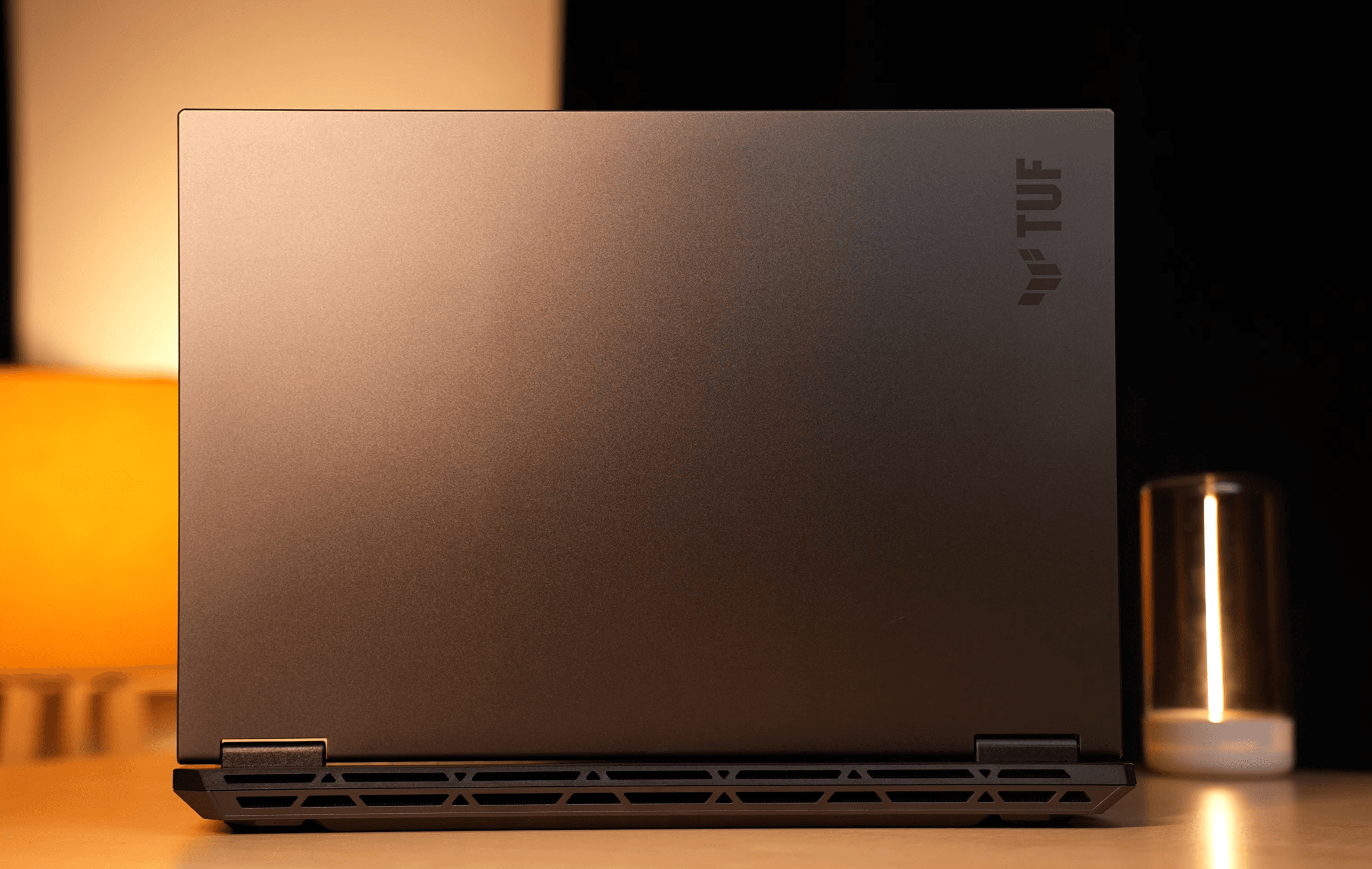 ASUS TUF Gaming laptop lid back view in Mecha Gray featuring the TUF logo, matte finish, and trapezoidal cut-out design for airflow.