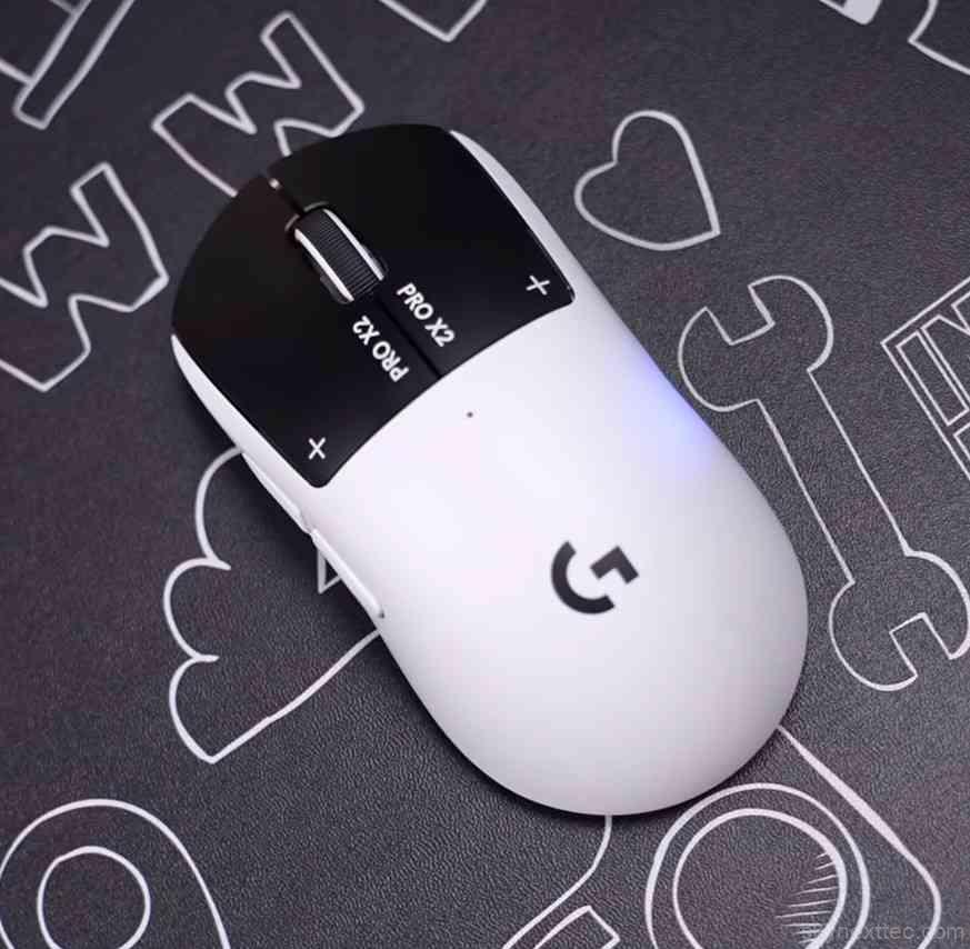 Top view of Logitech Pro X2 Superlight gaming mouse placed on a patterned mousepad, showing black top shell, white body, scroll wheel, and G logo.