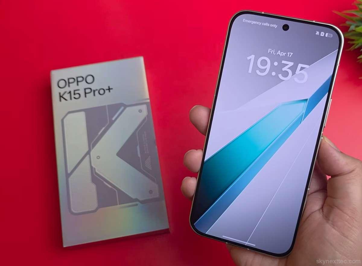 Oppo K15 Pro+ smartphone held in hand with retail box in background on red surface